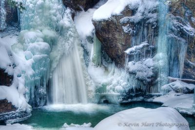 Bingham Falls in Vermont, half flowing and half frozen, surrounded by blue ice.
