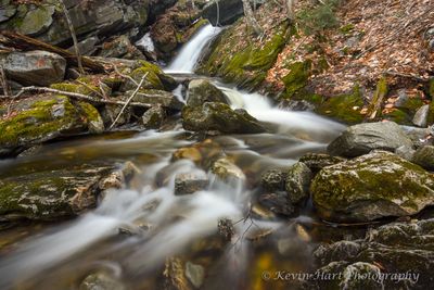 A brook drops over a small ledge and bends a corner in this long exposure shot.